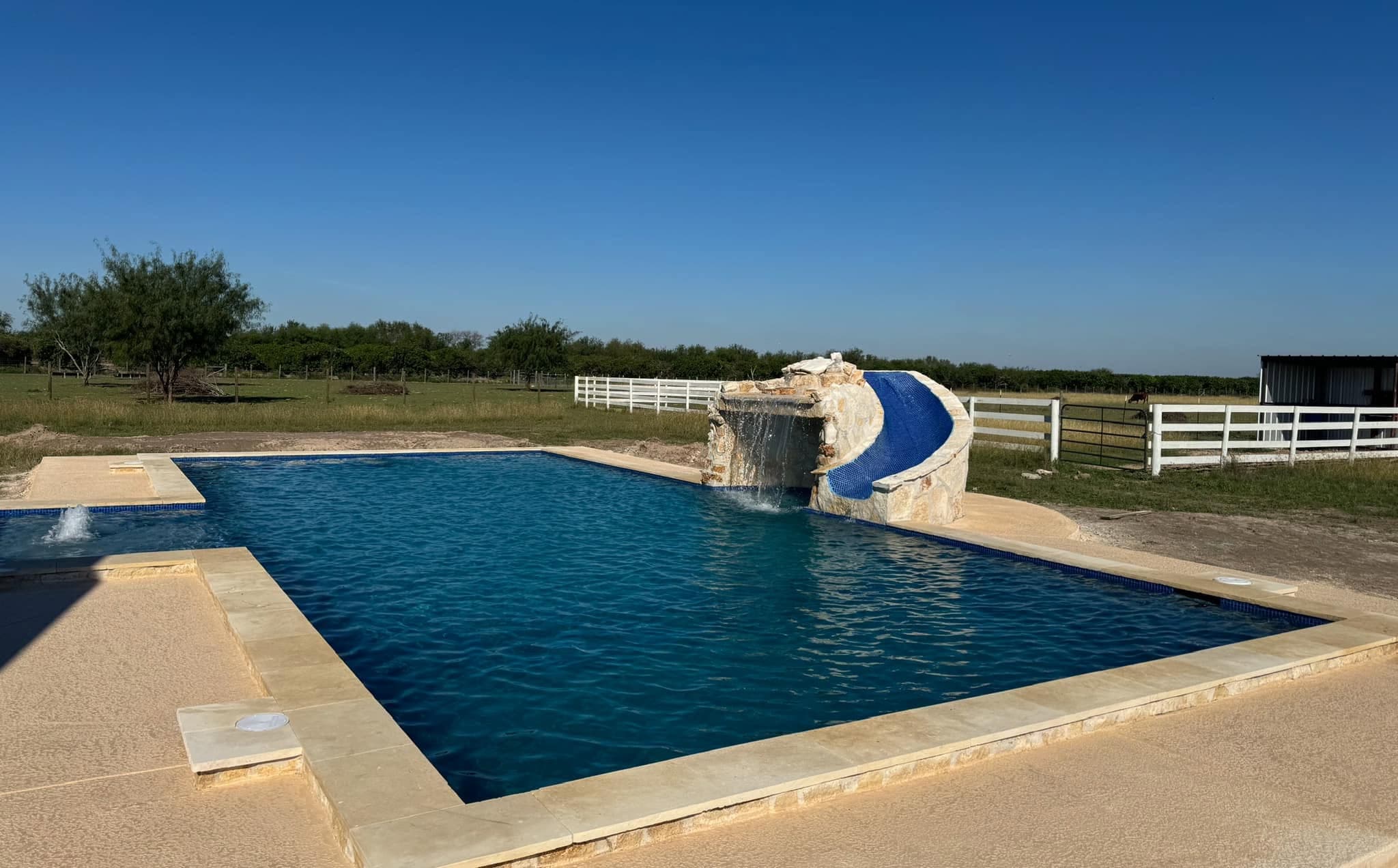Resort-style pool with stone waterfall and slide on South Texas ranch land